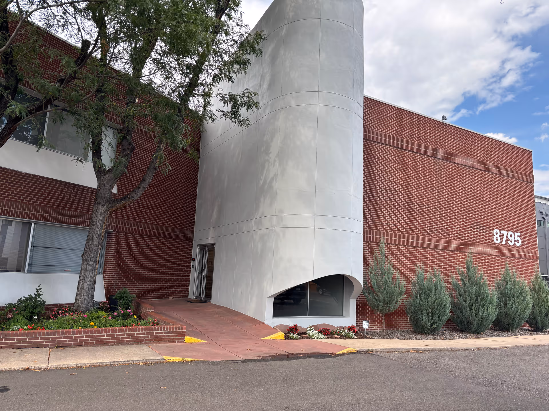 Magnolia Healthcare building with curved concrete entrance, red brick facade, and landscaped shrubs.