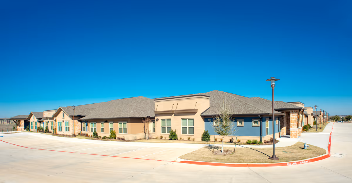 Single-story senior living facility exterior under a clear blue sky.