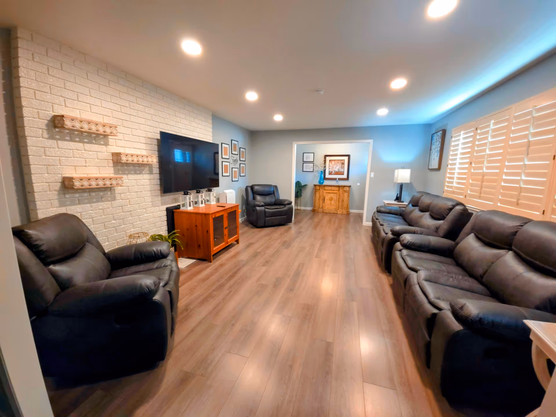 Spacious living room in a senior facility with leather sofas, wood floors, and a TV.