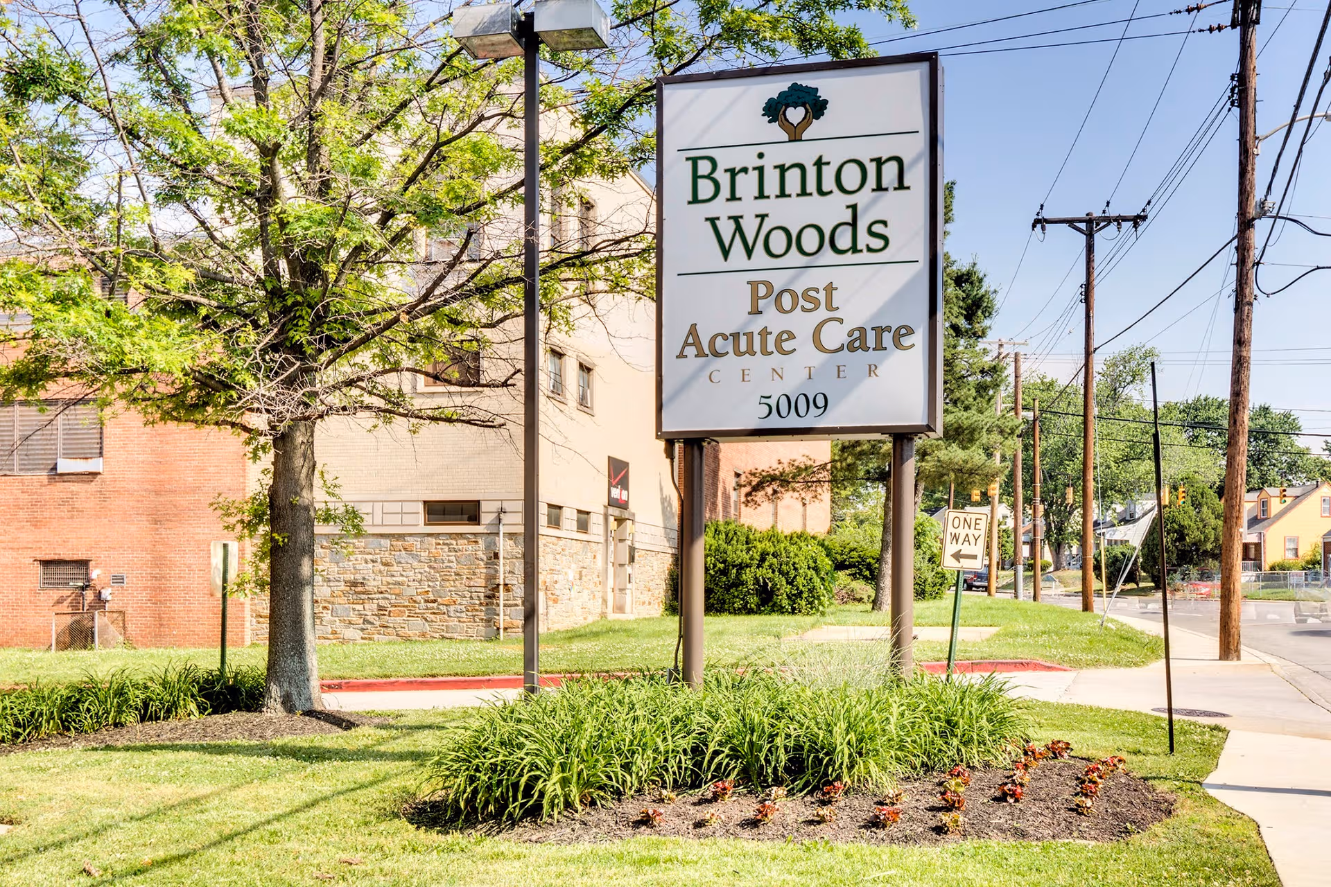 Brinton Woods Post Acute Care Center sign in front of a brick building with trees