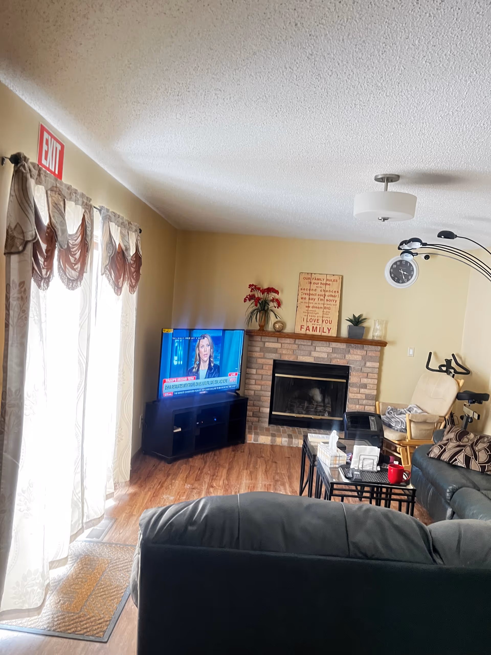 Cozy living room with fireplace, TV, sofa, coffee table, and curtained windows.