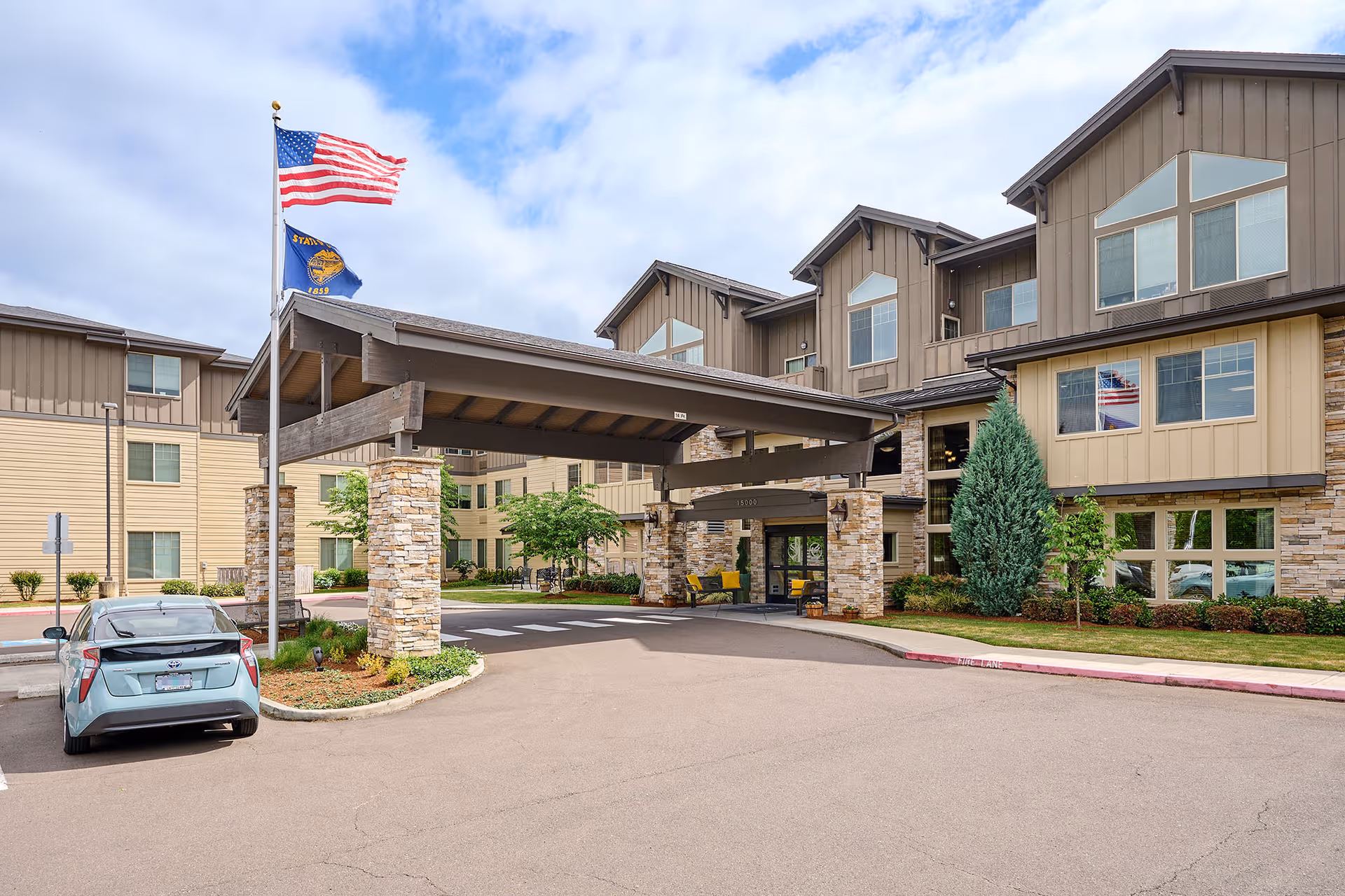 Exterior view of Bonaventure of Tigard senior living facility with entrance canopy and flags.