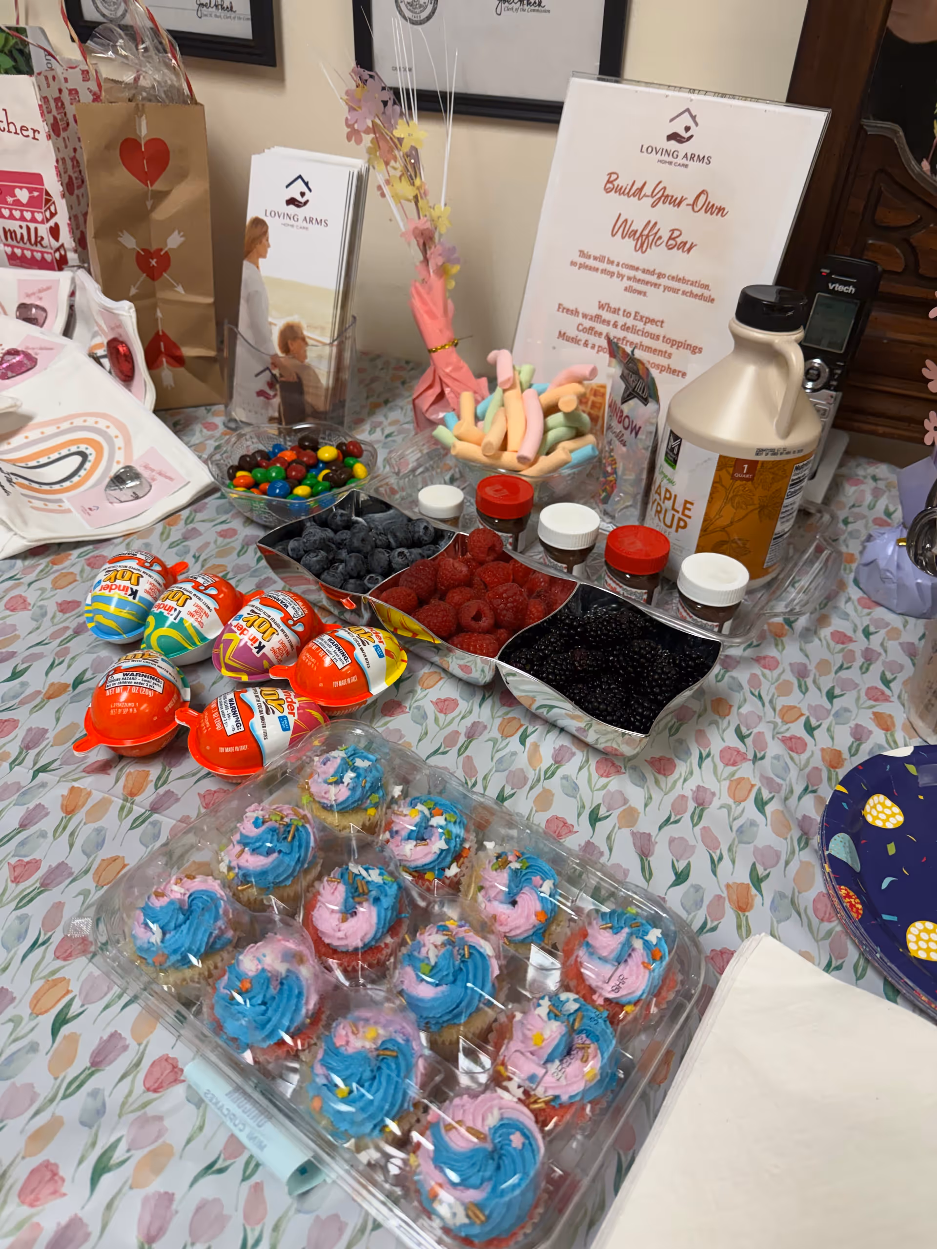 Table spread with colorful cupcakes, berries, candy, and a Build-Your-Own Waffle Bar sign.
