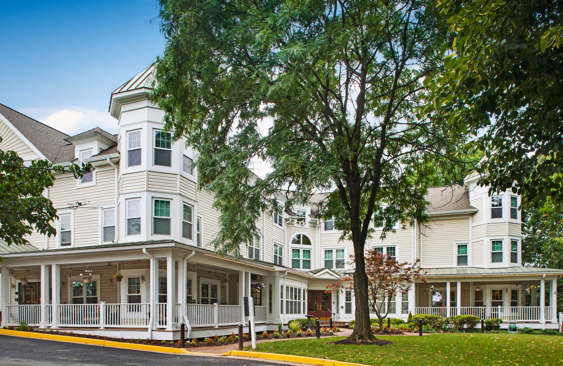 Sunrise of Arlington exterior building with a wraparound porch and large tree in front.