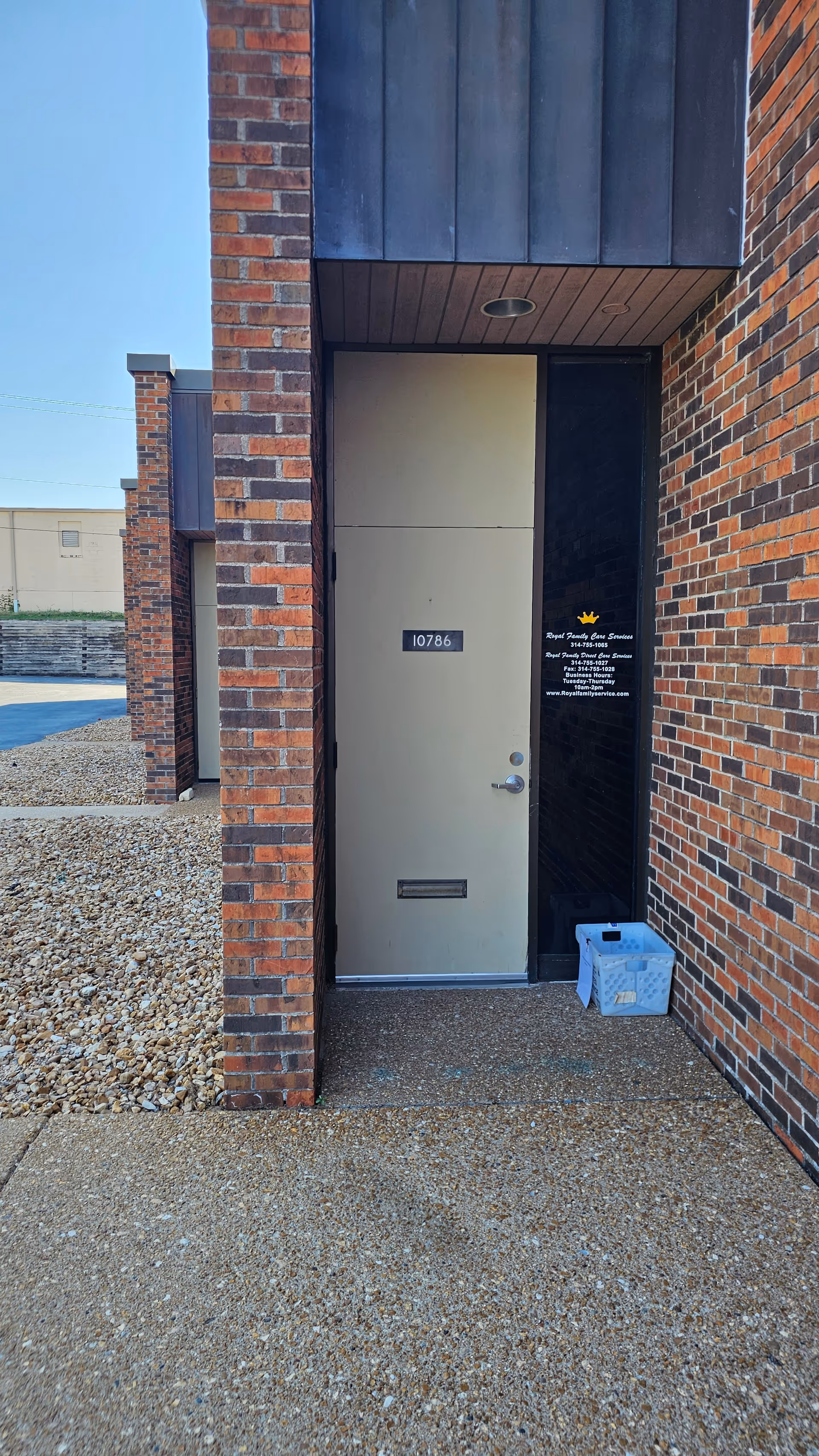 Exterior brick entrance with a beige door labeled 10786 and a blue crate nearby.