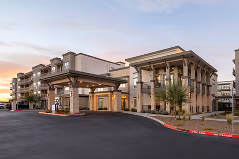 Exterior view of a senior living facility with a covered drop-off entrance and parking lot.