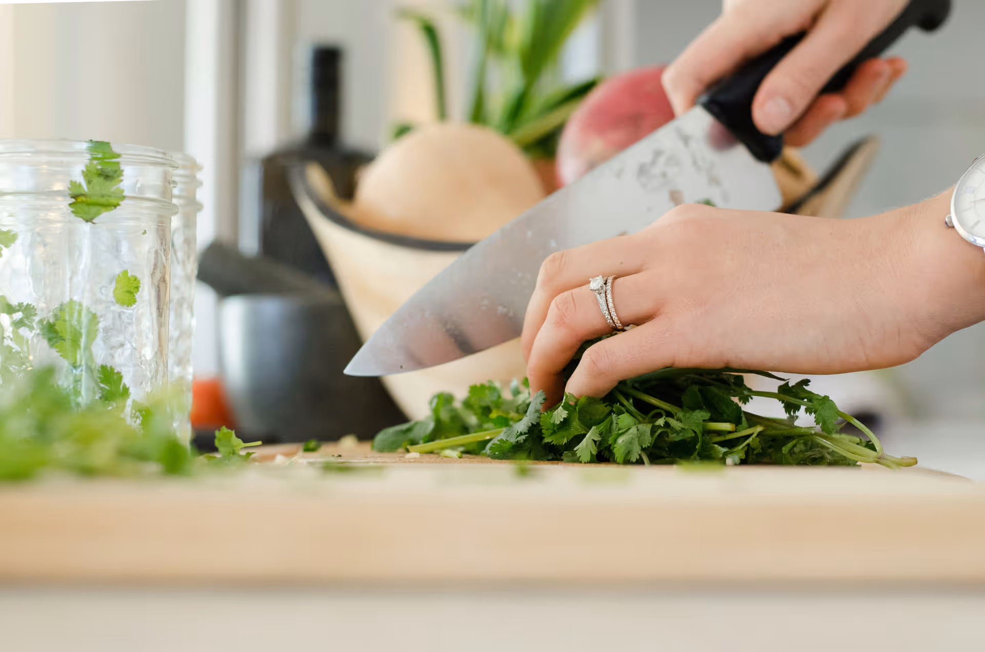 Close-up of a person slicing fresh herbs on a kitchen counter.