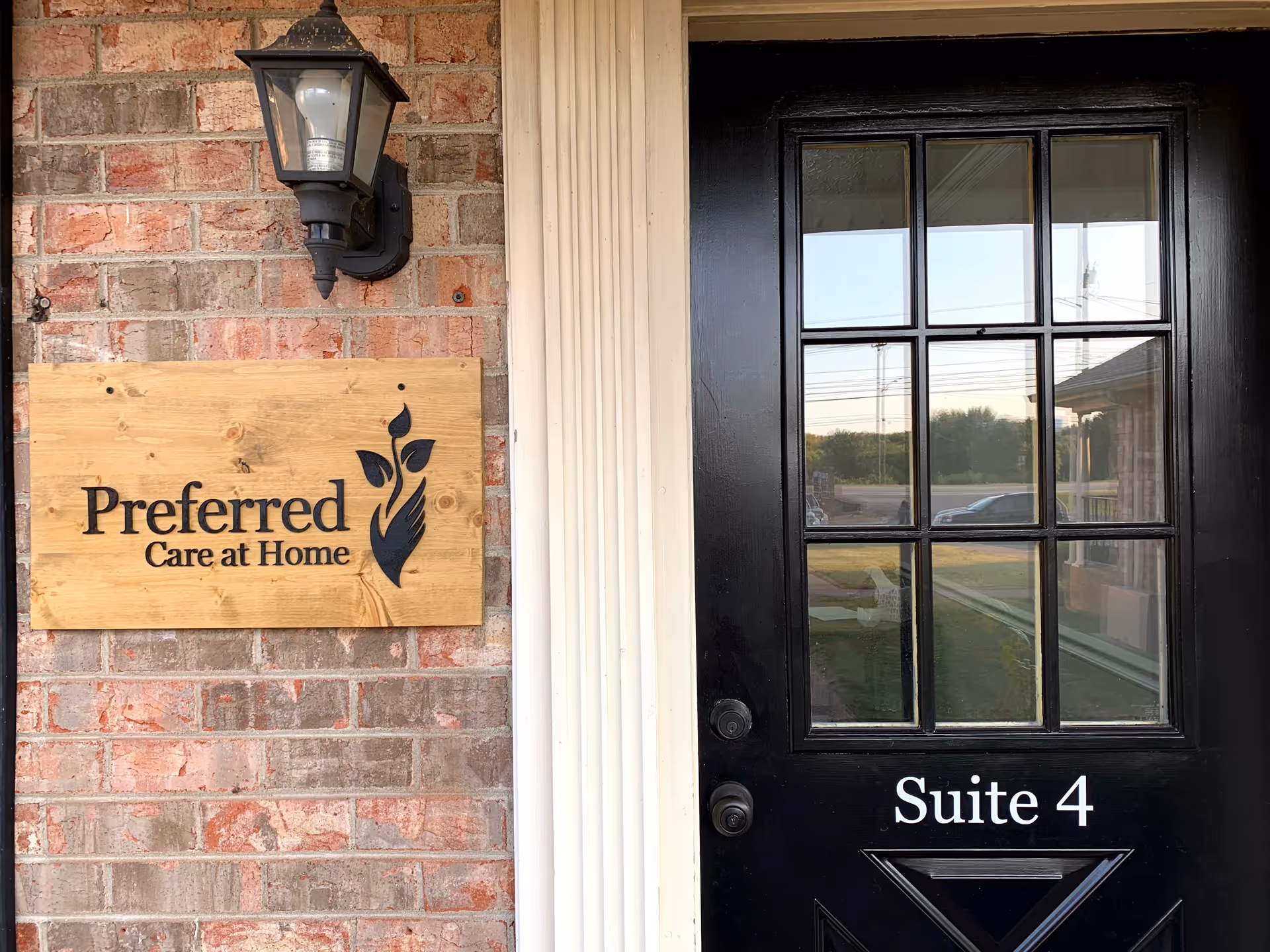 Exterior brick entrance with wooden sign 'Preferred Care at Home' beside a black door Suite 4.