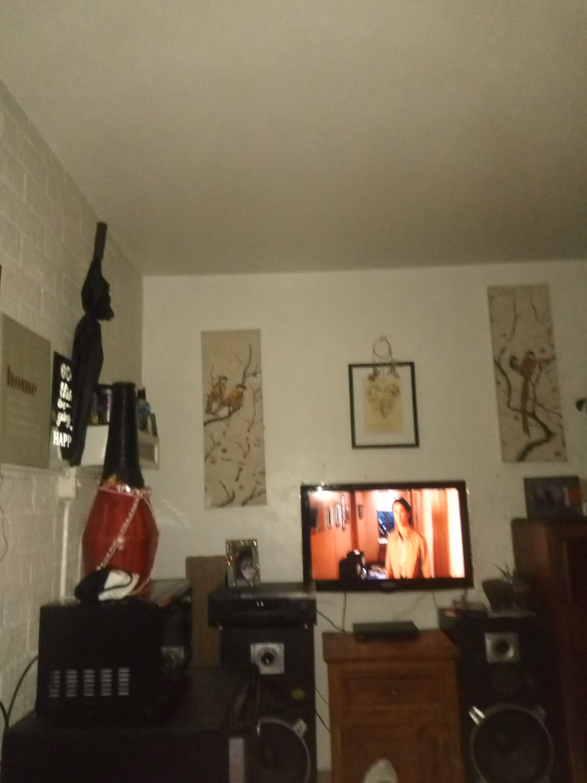 Living room with a TV on a stand, speakers, and decorative wall art.