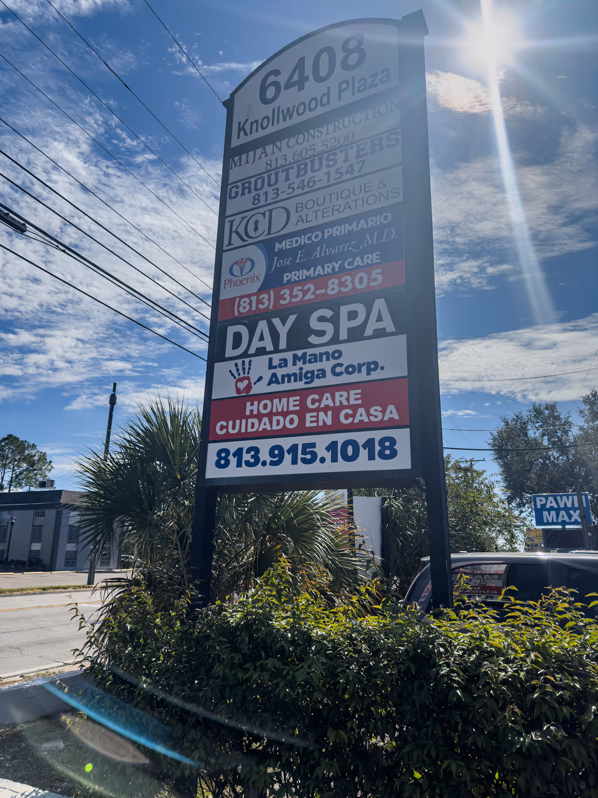 A tall outdoor signboard advertises La Mano Amiga Corp and other businesses.