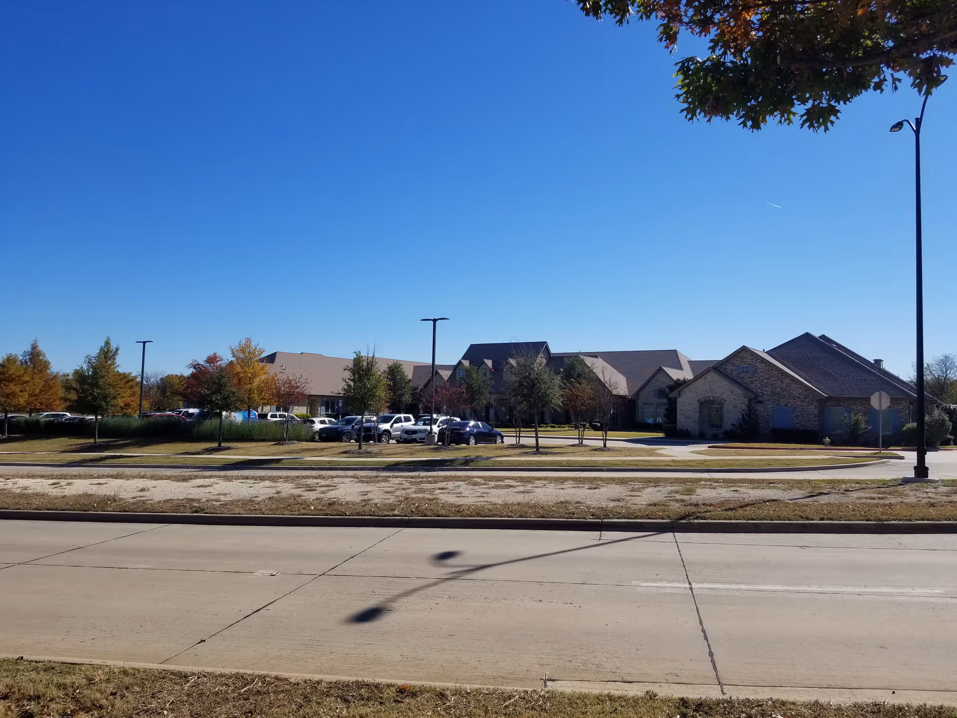 Single-story senior living building with a parking lot and clear blue sky in the foreground.