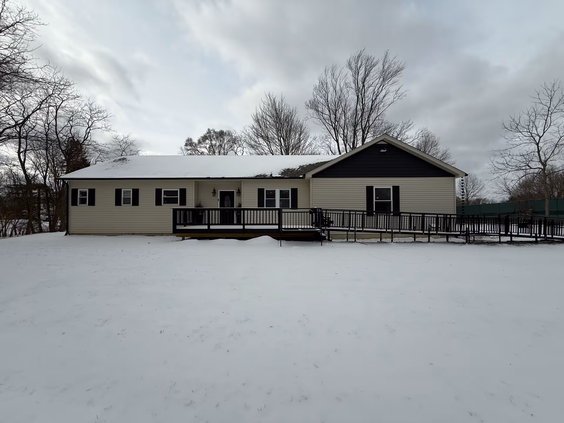 Single-story beige senior living facility with a ramp and snow-covered yard.