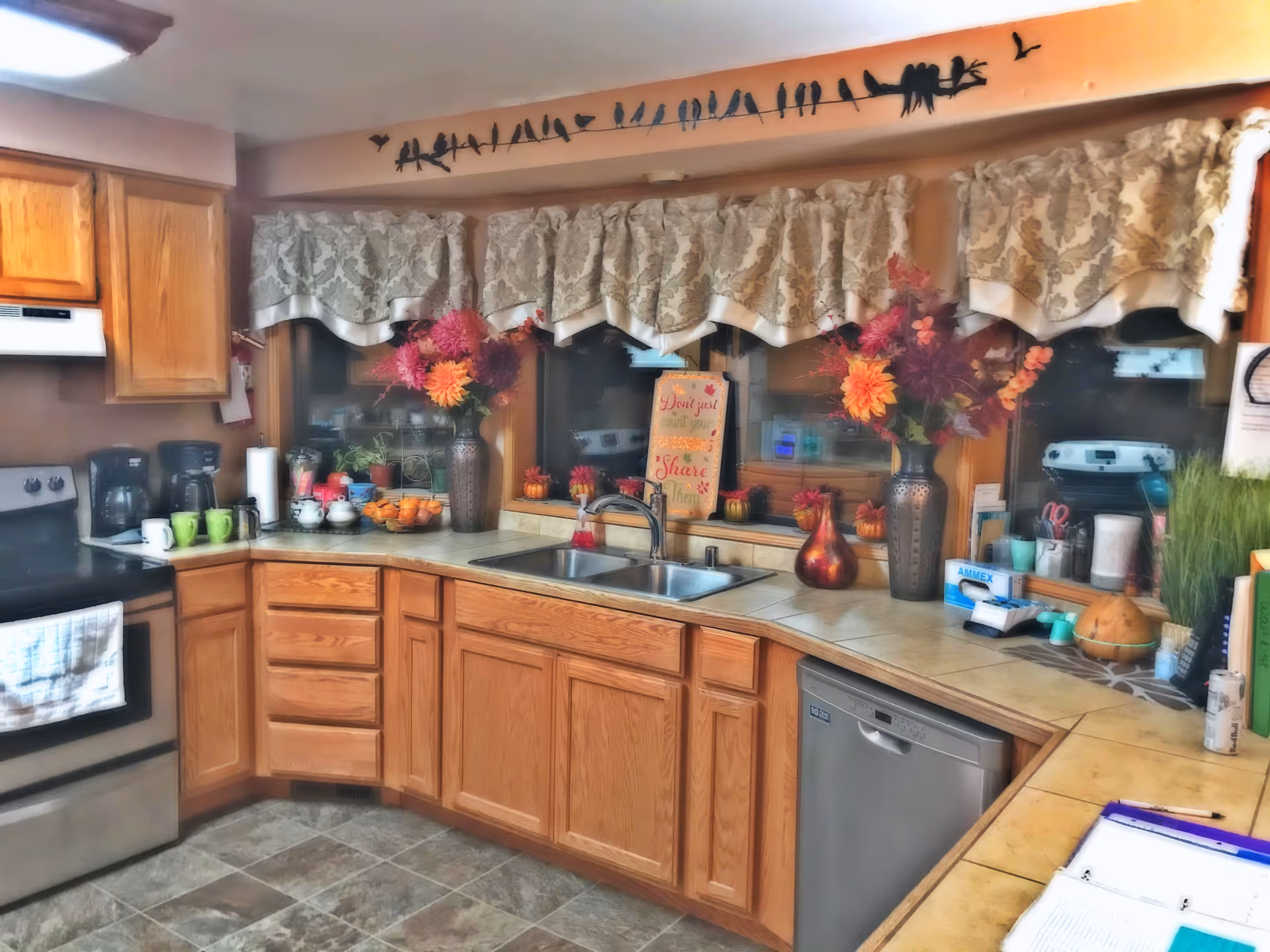 Cozy U-shaped kitchen in Pioneer House with wooden cabinets, sink, and autumn decorations.