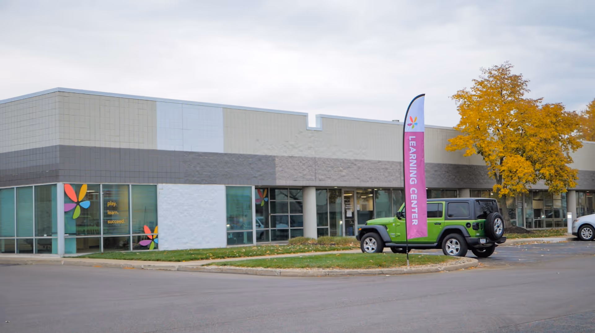 Exterior view of a modern building with colorful window decals and a learning center banner