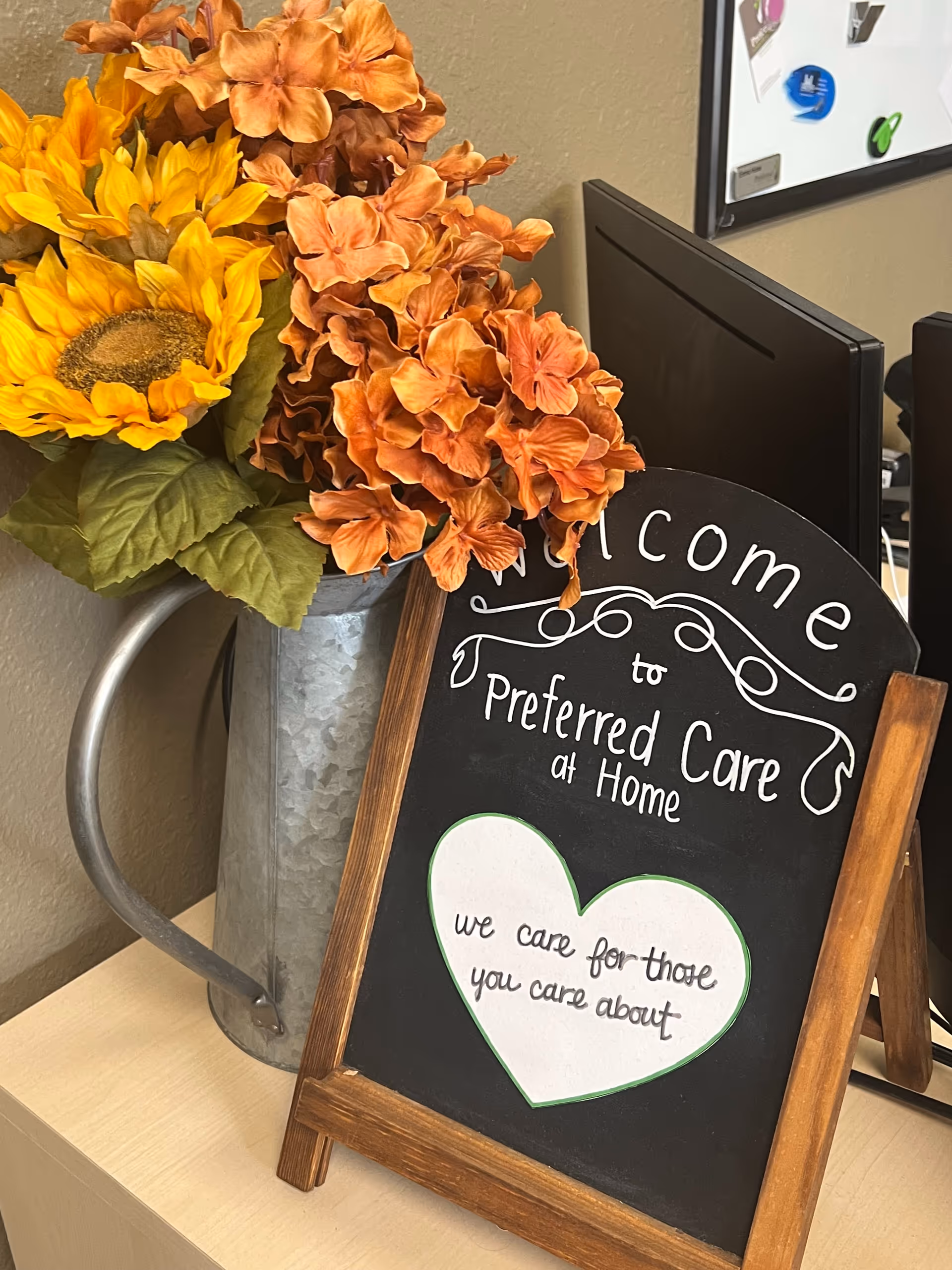 Interior desk area featuring a welcome sign and a metal pitcher with flowers.