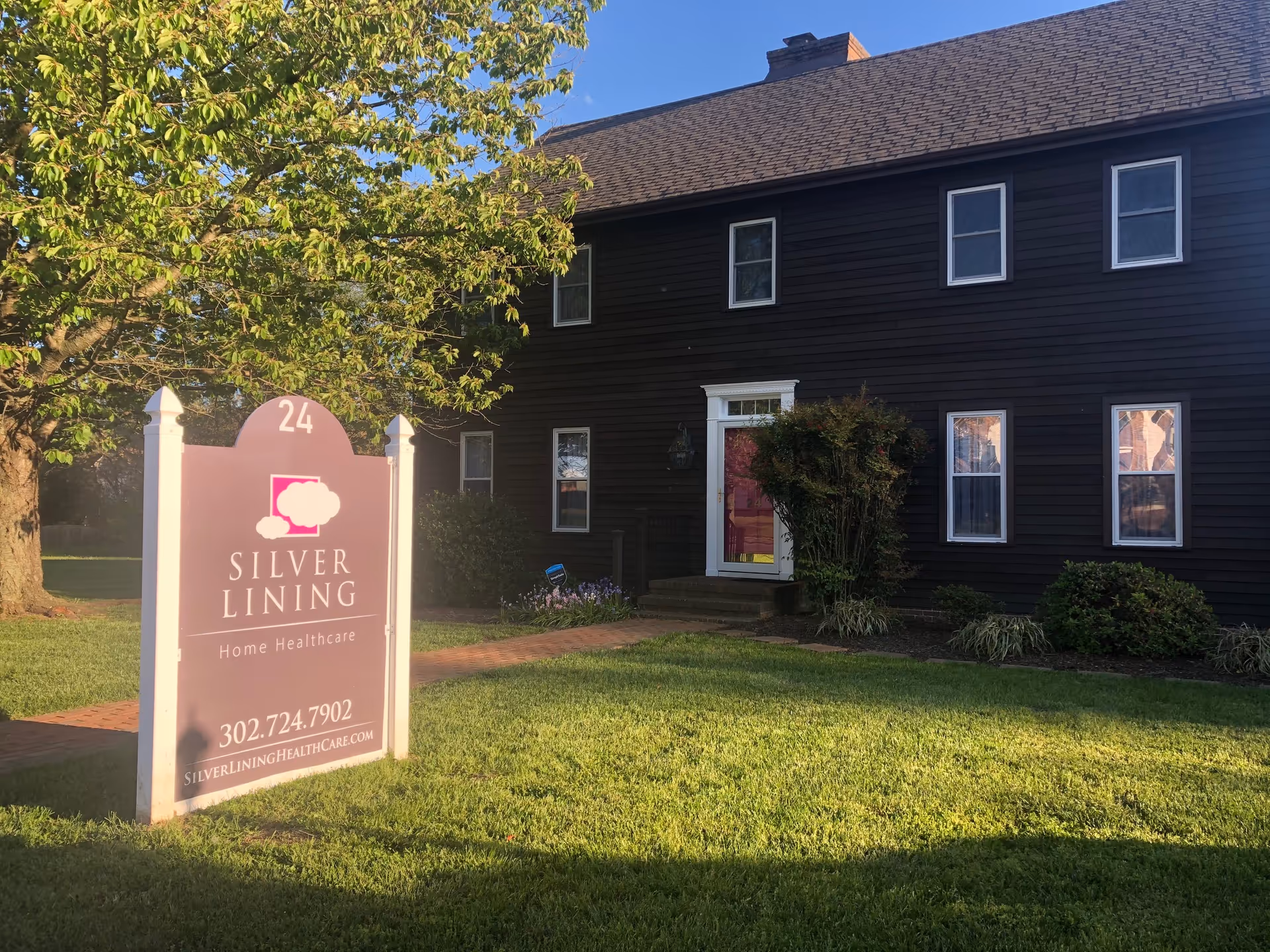 Exterior view of Silver Lining Home Healthcare building with a large pink sign in front.