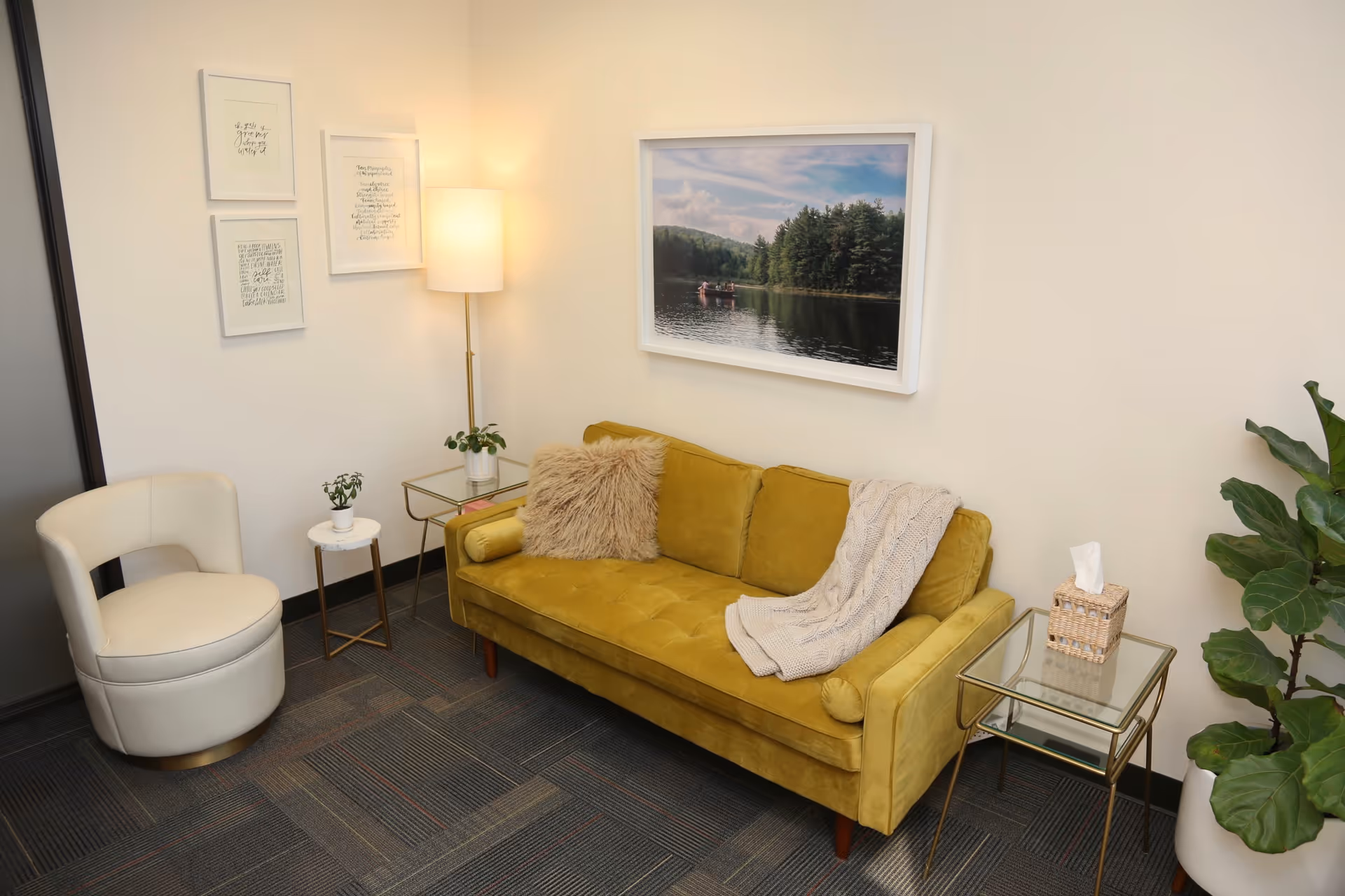 Modern senior living lounge with mustard sofa, white chair, plants, and framed wall art.
