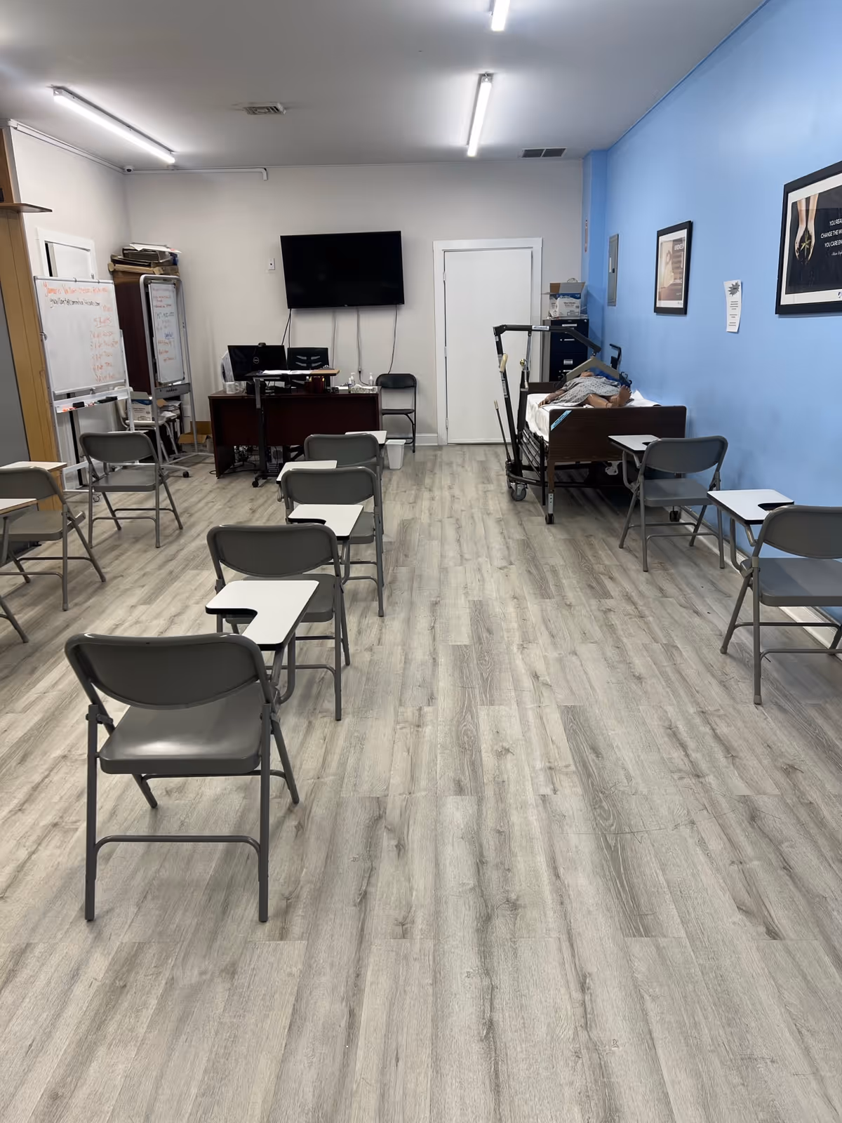 Empty training room with chairs facing a desk and wall-mounted TV.
