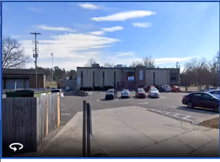 Front view of a beige facility with a parking lot and blue sky.