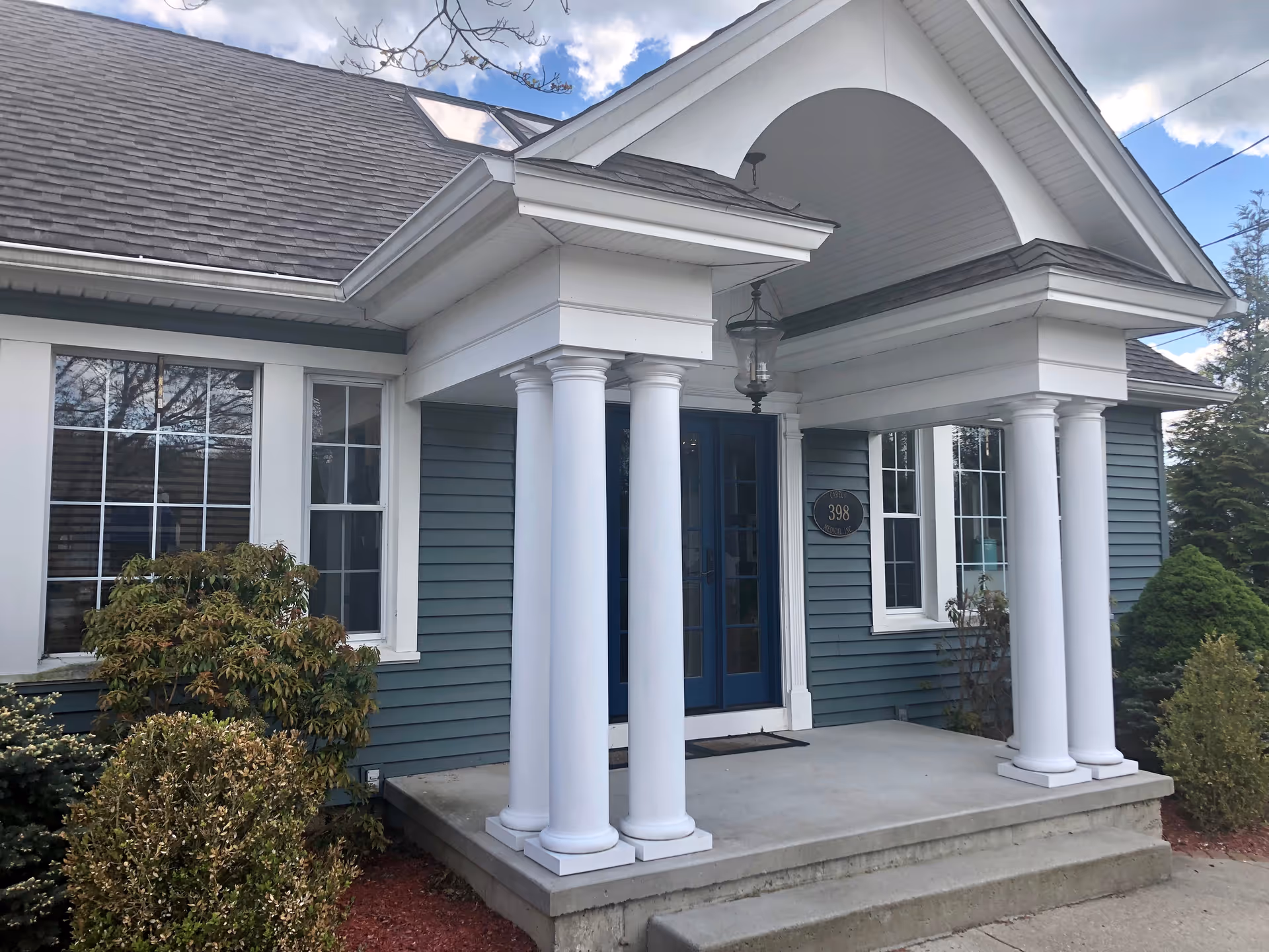 Blue-gray building with white columns and a front porch entrance.