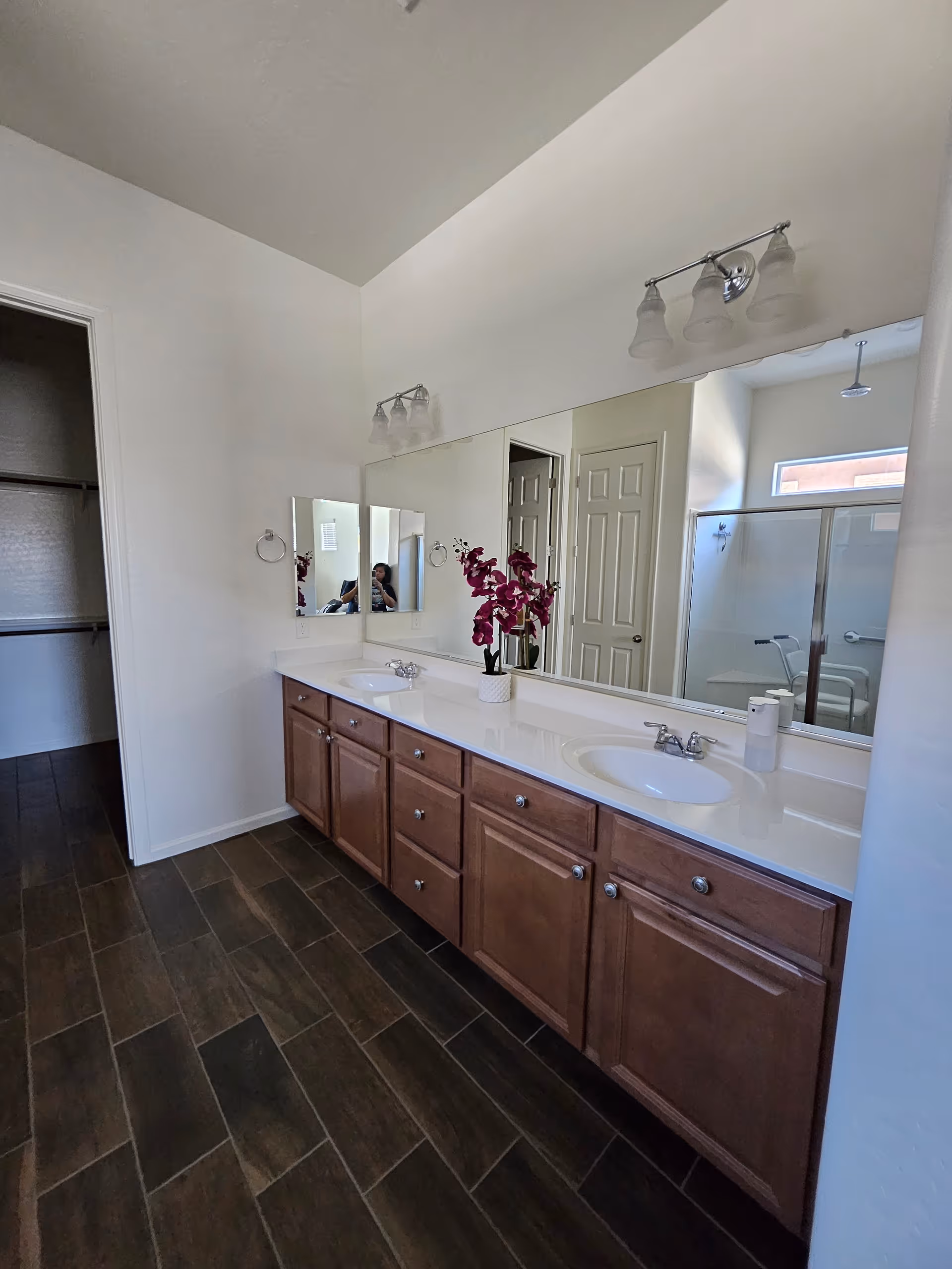 Senior living facility bathroom with double sinks, mirrors, and wood cabinets.