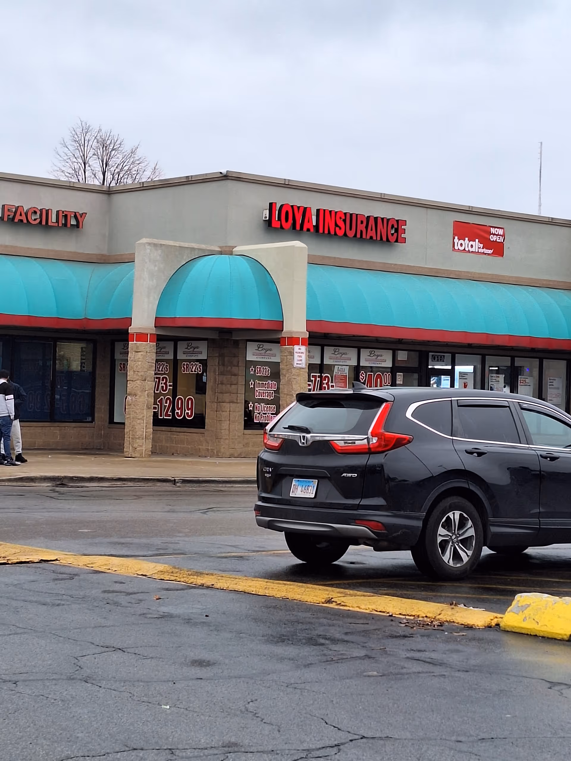 Exterior view of a strip mall storefront with LOYA INSURANCE signage and a parked SUV.