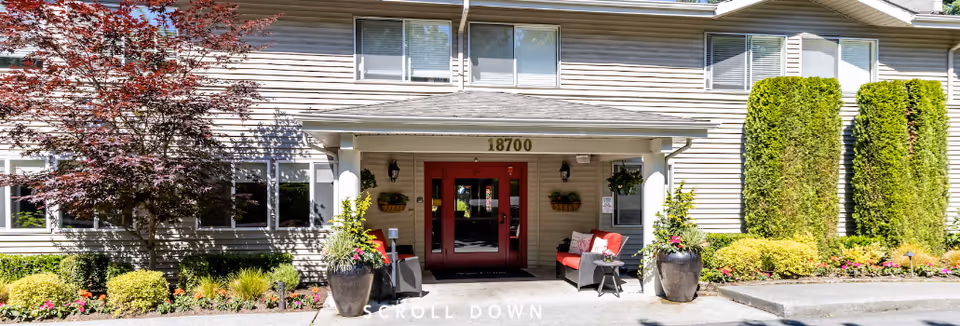 Exterior view of the Aegis Living Lynnwood entrance with red doors and seating.