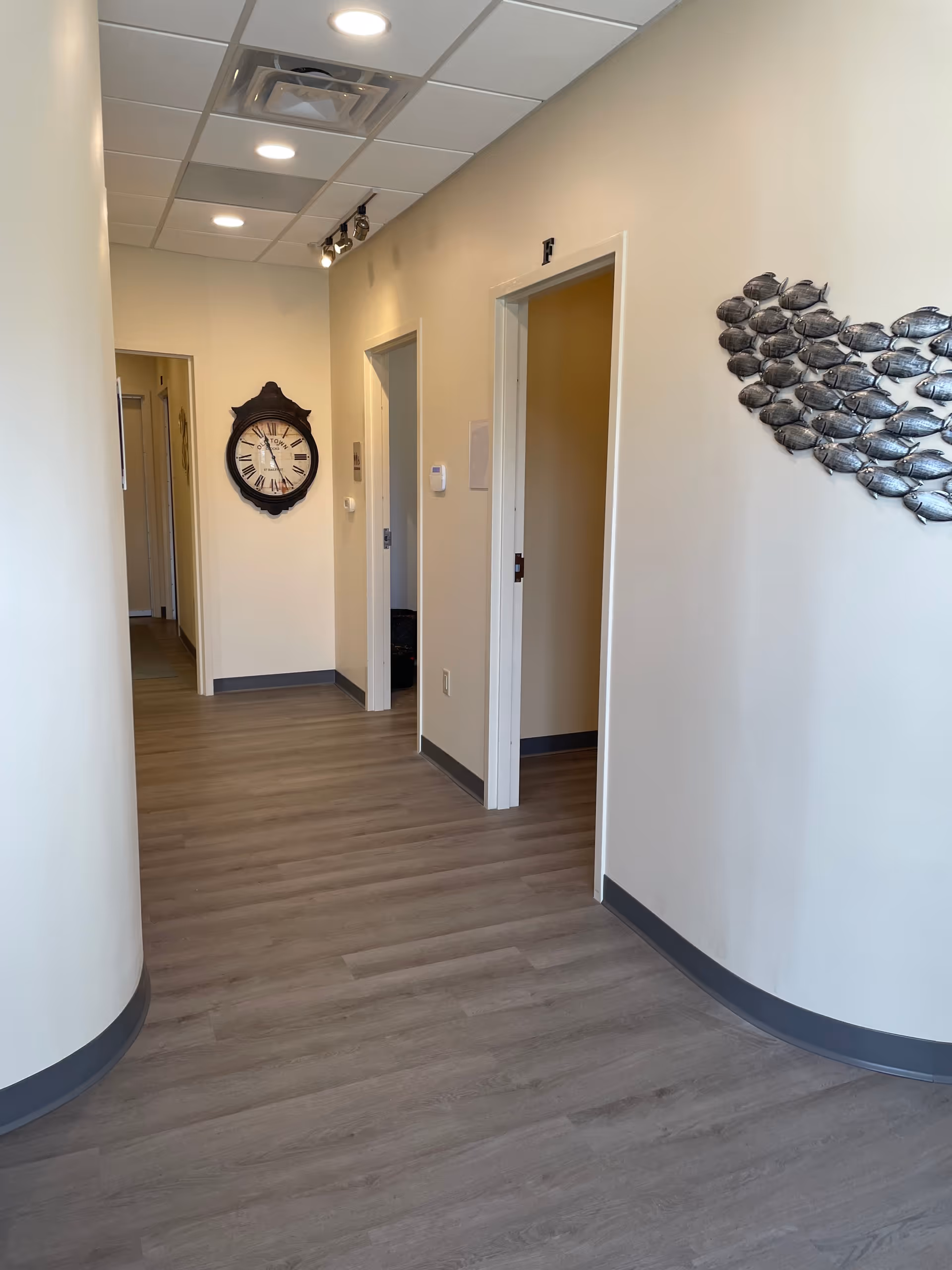Interior hallway of a senior living facility featuring curved wall and clock.