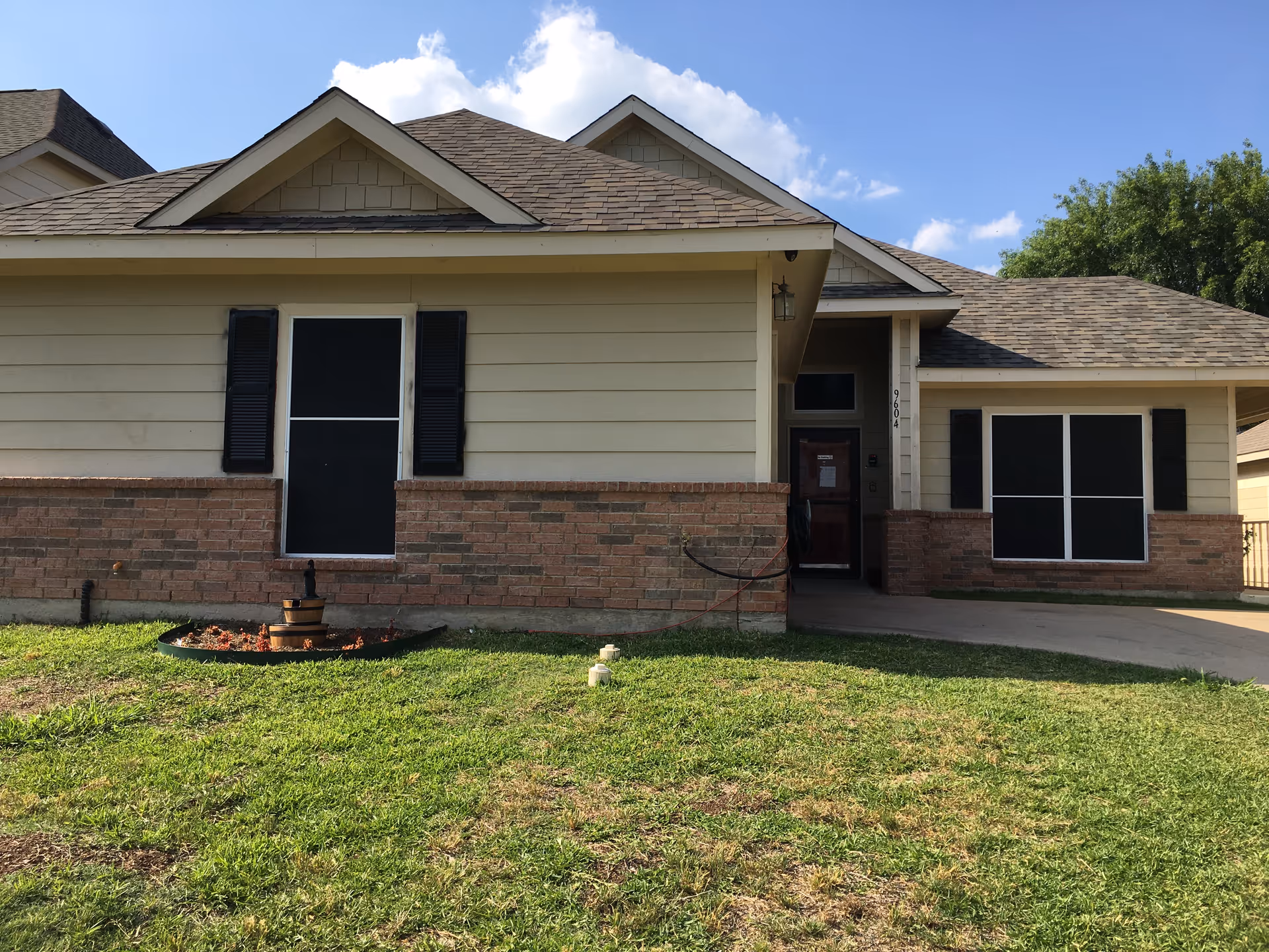 Front exterior of a single-story senior living facility with beige siding and brick base.