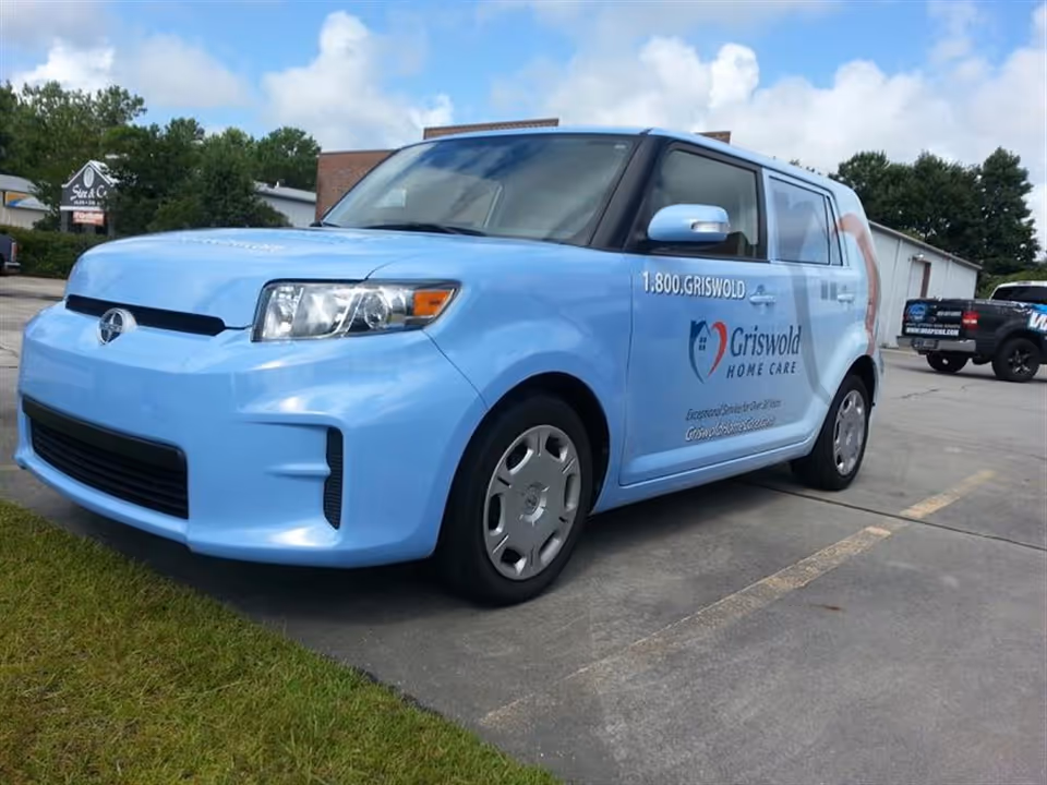 Light blue Griswold Home Care van parked in a parking lot.