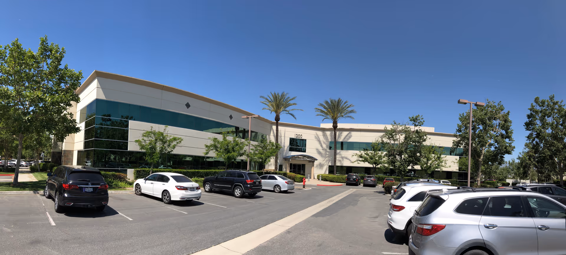 Exterior view of a modern two-story office building with a parking lot.