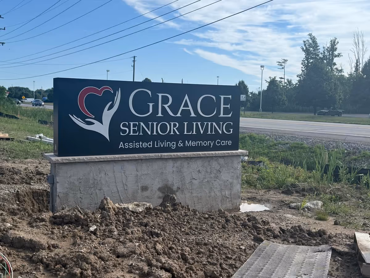 Grace Senior Living sign on a blue panel beside a road.