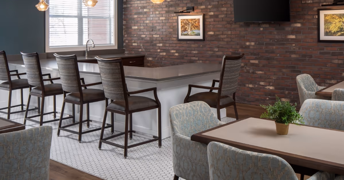Brick-walled dining area with bar-height seating, tables, and a small plant centerpiece.