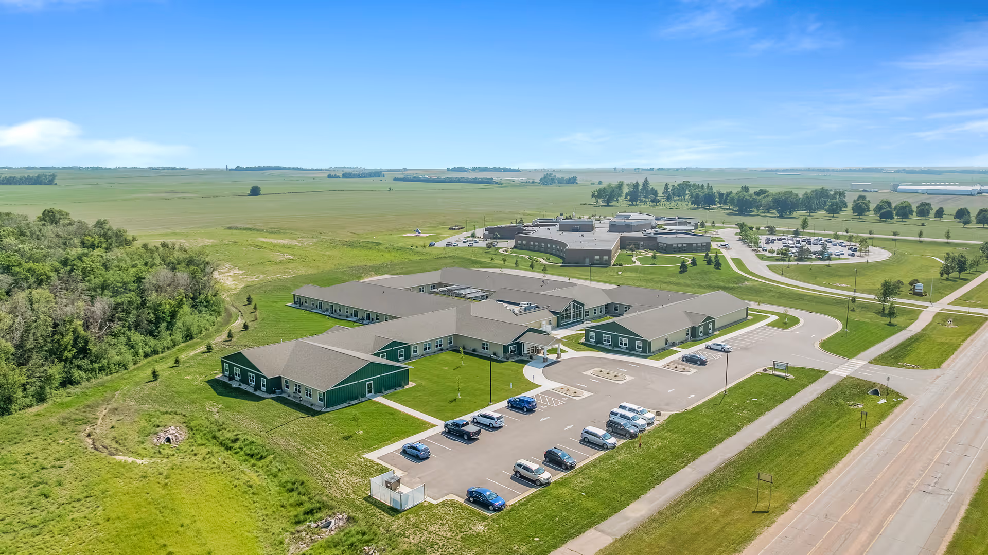 Aerial view of a Peaceful Pines Senior Living campus with multiple green-roofed buildings and parking