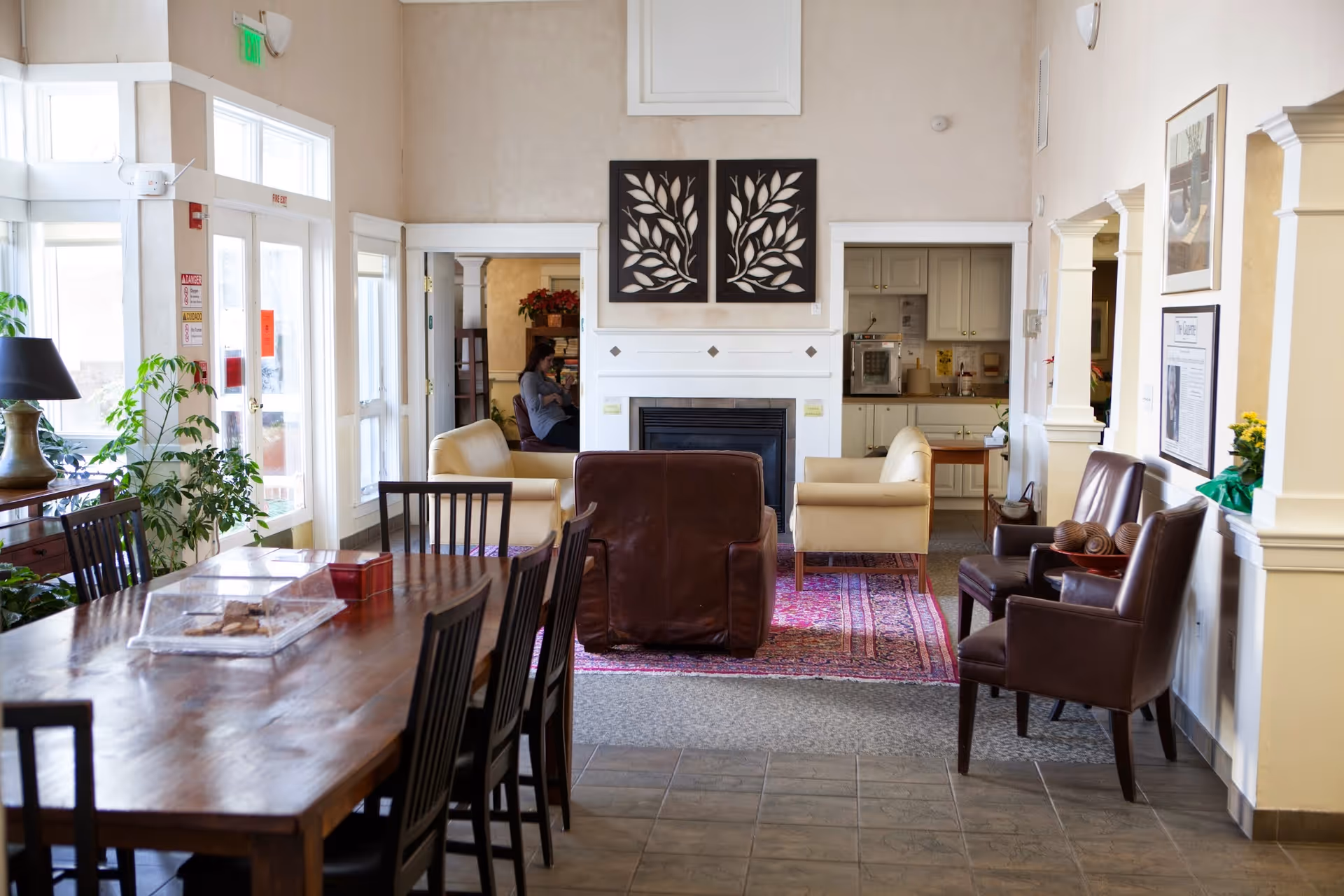 A cozy communal living area with sofas, chairs, a fireplace, and a dining table.