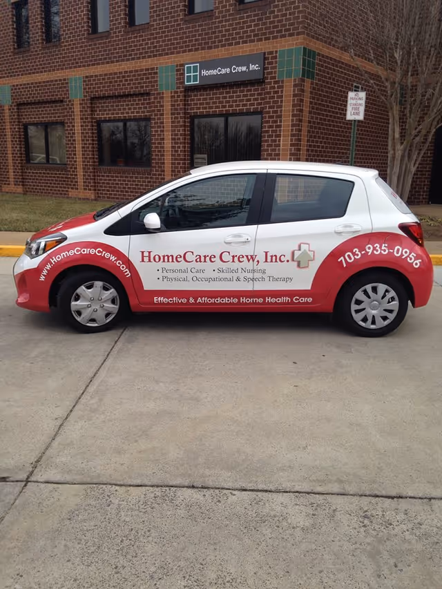 White and red HomeCare Crew van parked in front of a brick office building.