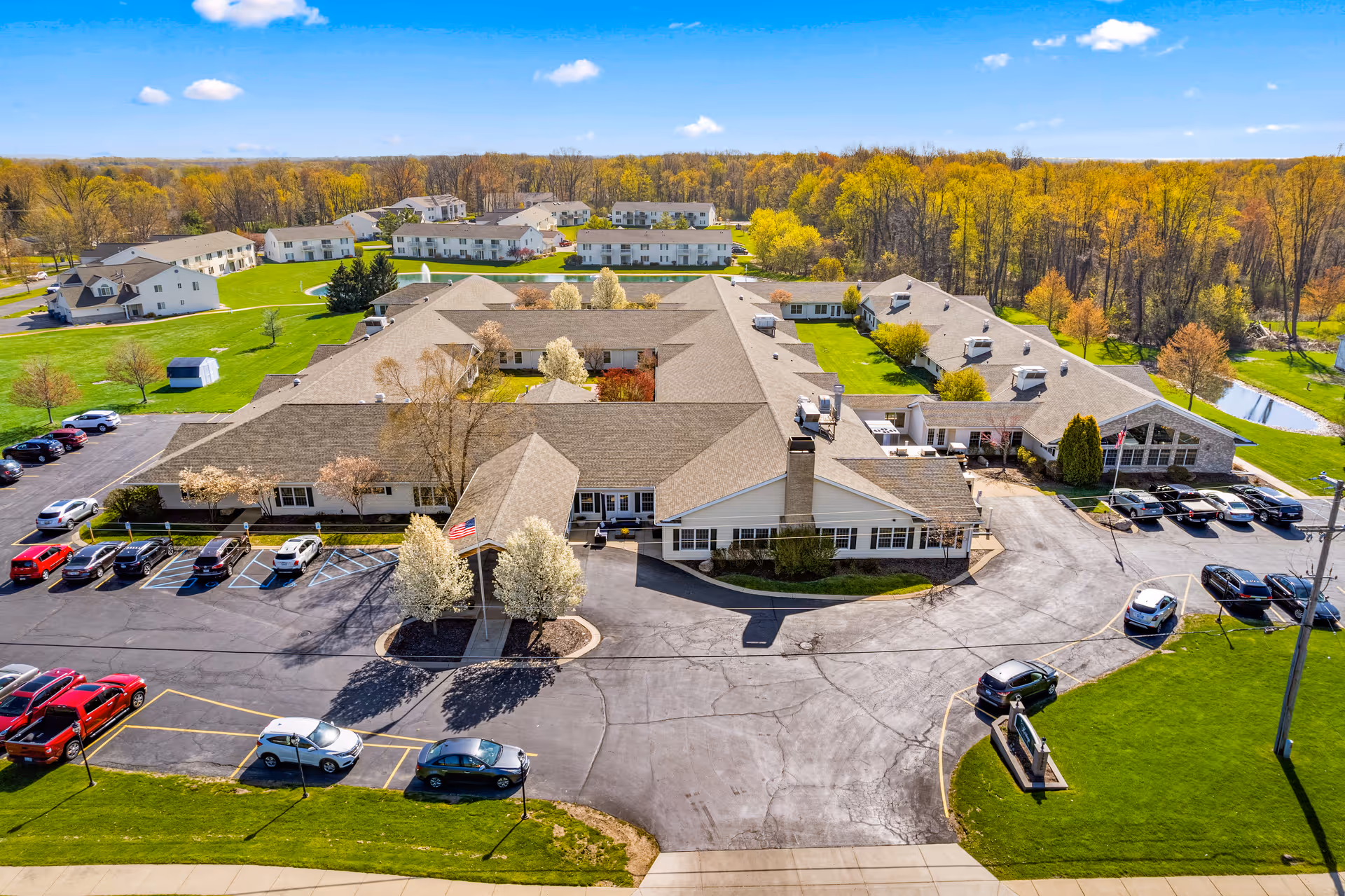 Aerial view of a large senior living campus with multiple buildings, parking, and green grounds.