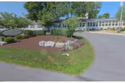Front exterior of Maple Farm Nursing Center with circular driveway and landscaped grounds.