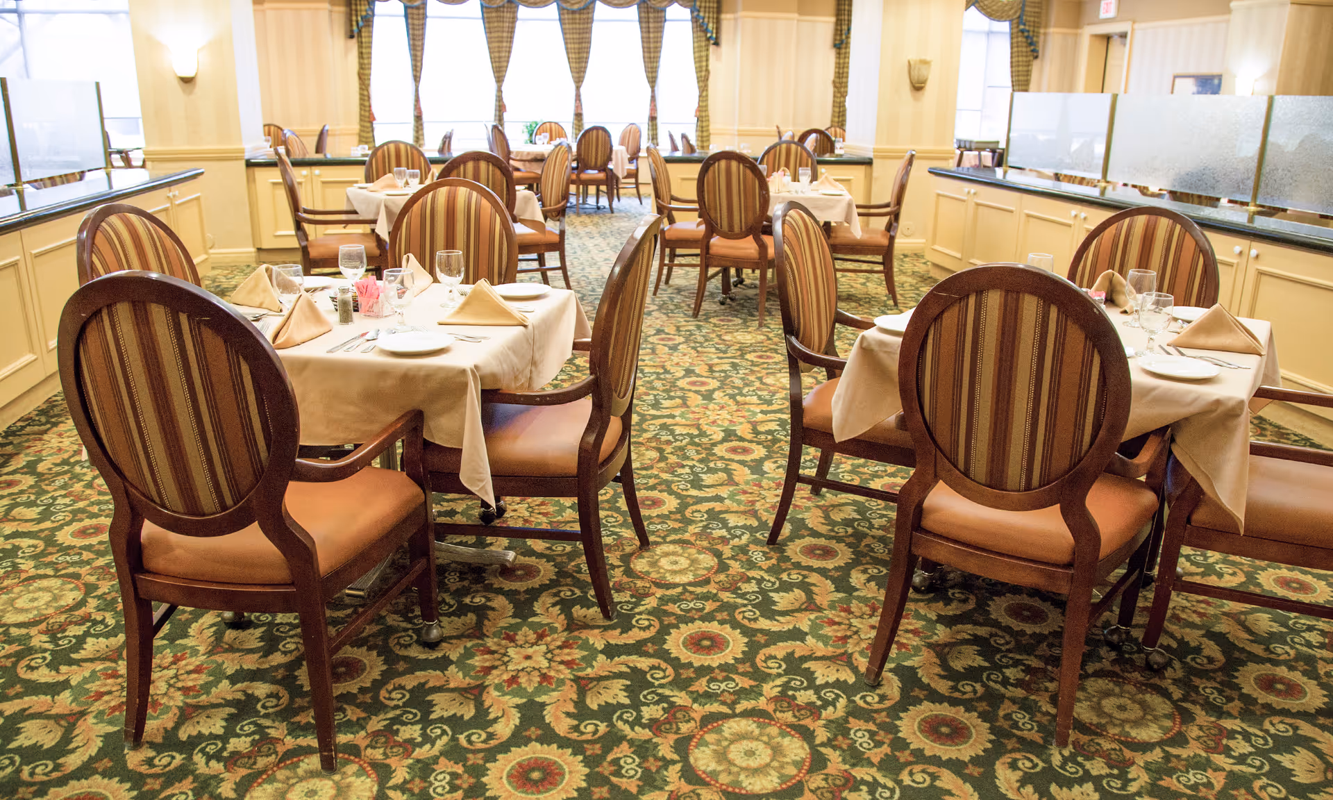 Elegant dining room with round tables, beige tablecloths, and striped chairs.