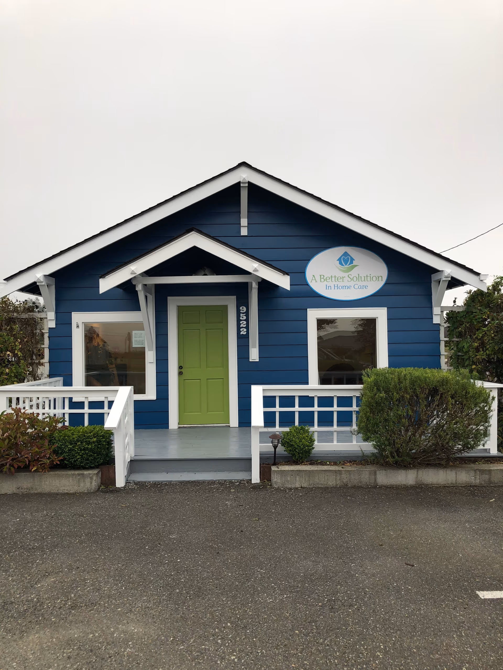 Blue, house-shaped senior care facility exterior with white trim, green door, and sign.