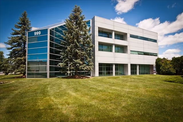 Exterior of a modern facility building with glass panels and green lawn.