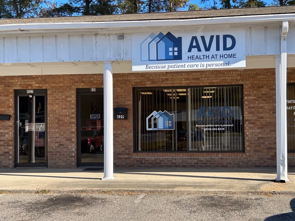 Brick storefront with AVID Health at Home sign and large front window.