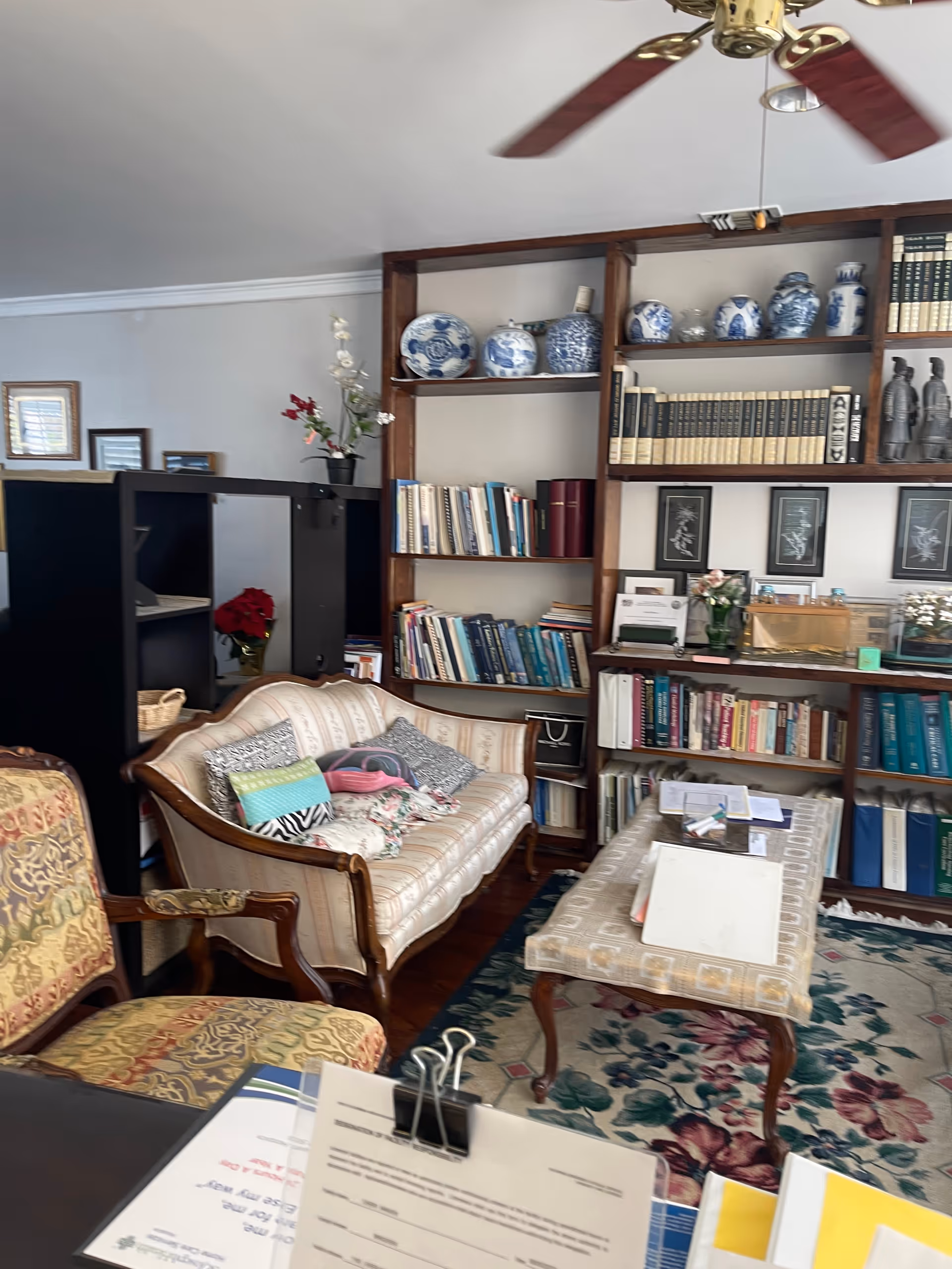 Cozy lounge with sofa, chairs, and a tall bookcase in a library-style living room.