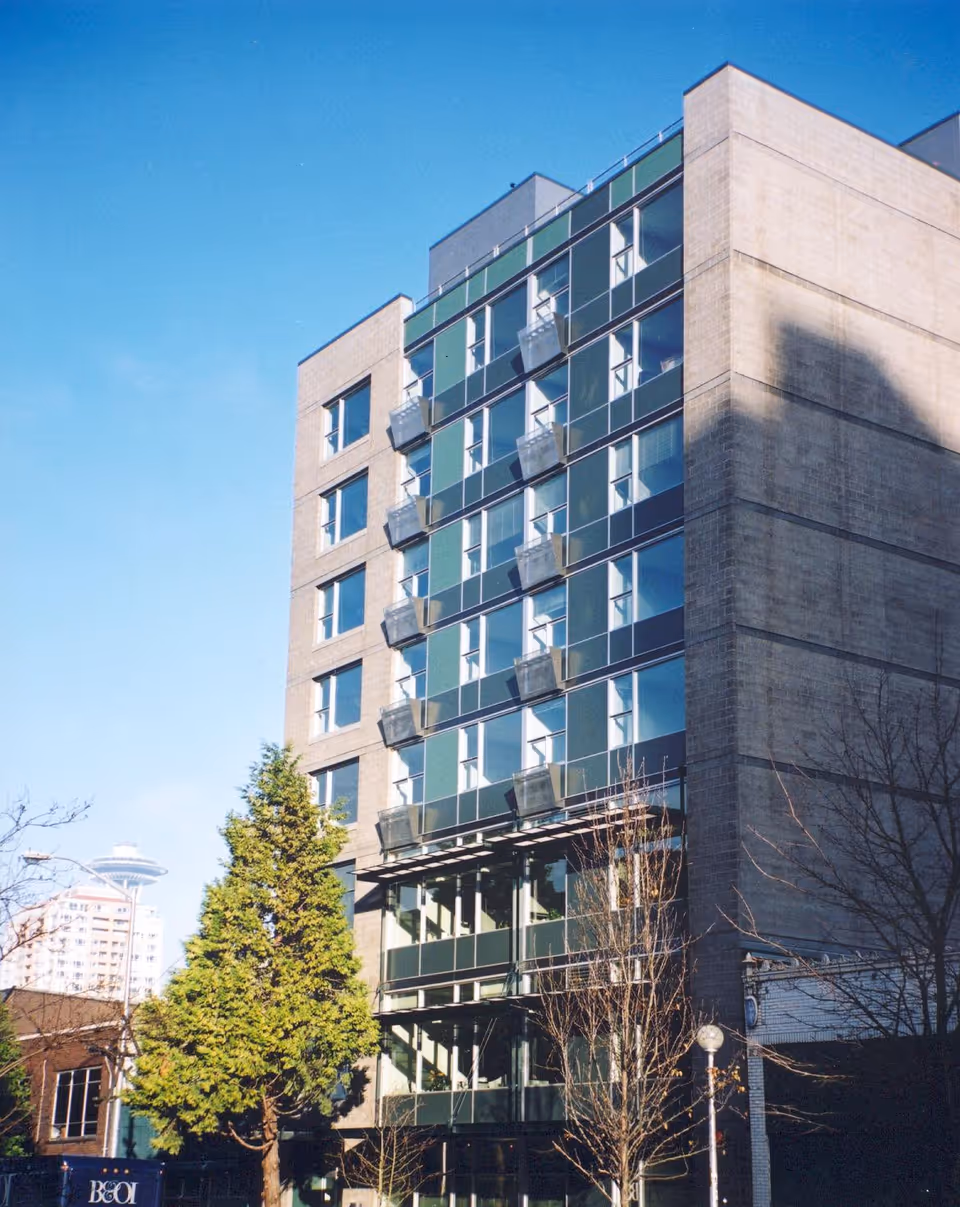 Tall modern apartment building with glass balconies under a blue sky