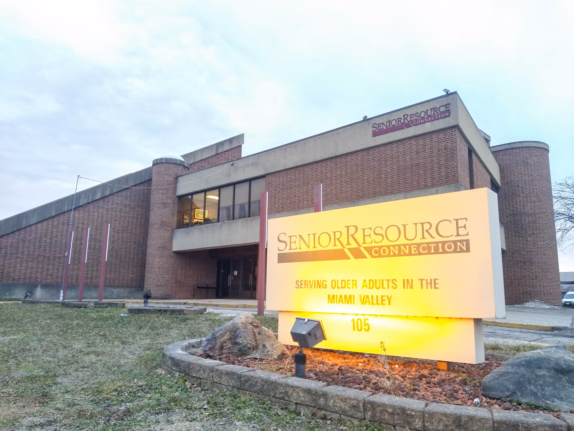 Exterior view of a brick Senior Resource Connection building with a large illuminated sign.