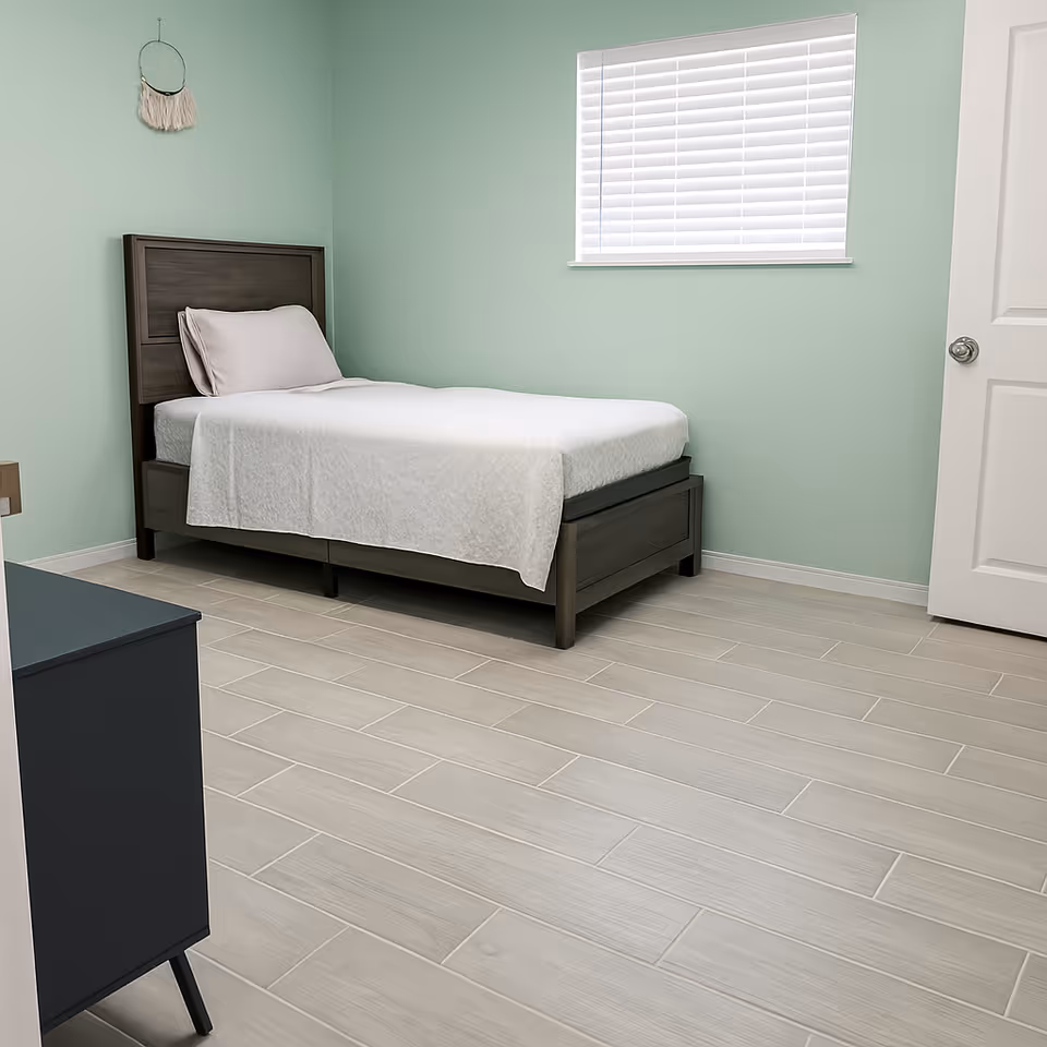 Terrace Rose bedroom with a single bed, mint-green walls, and window blinds.
