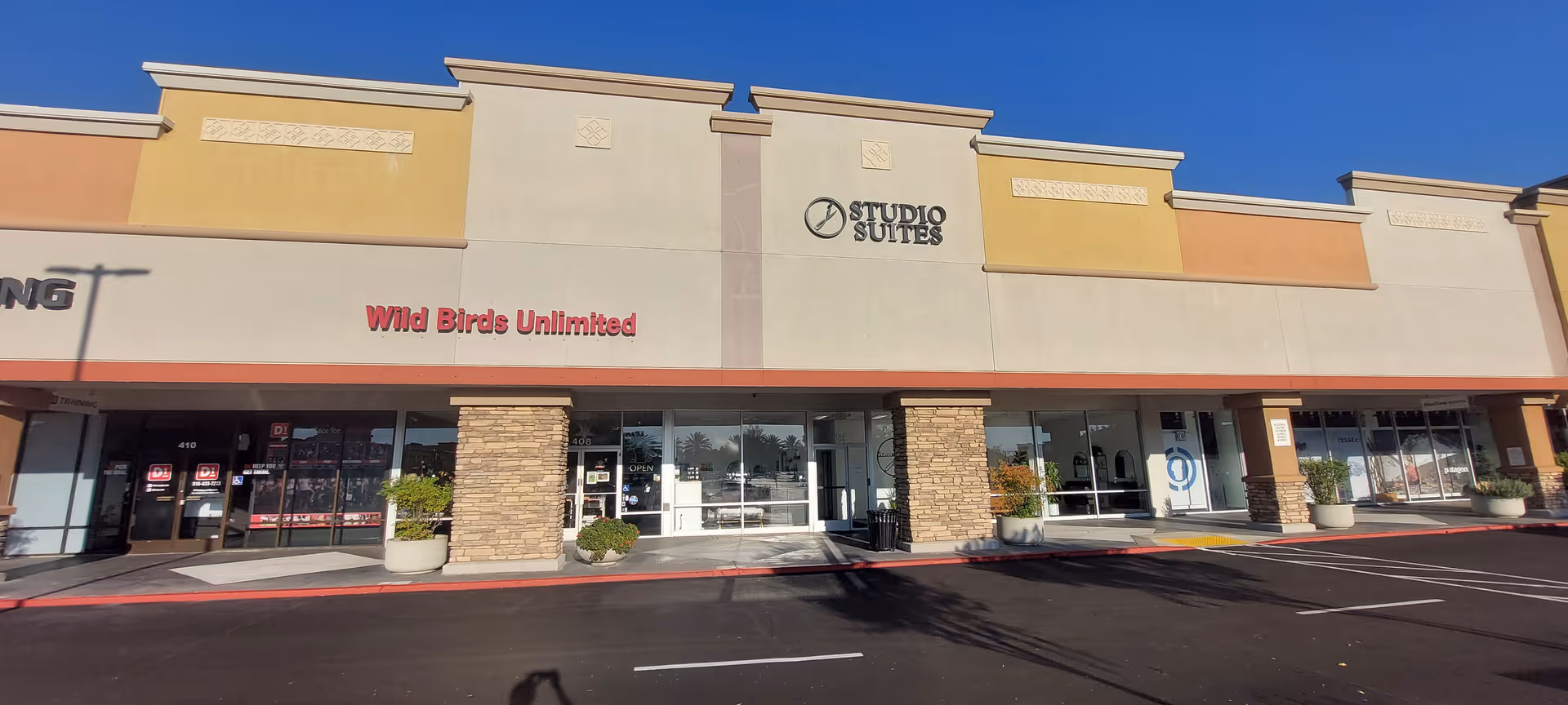 Exterior of a strip mall with Wild Birds Unlimited and Studio Suites storefronts.