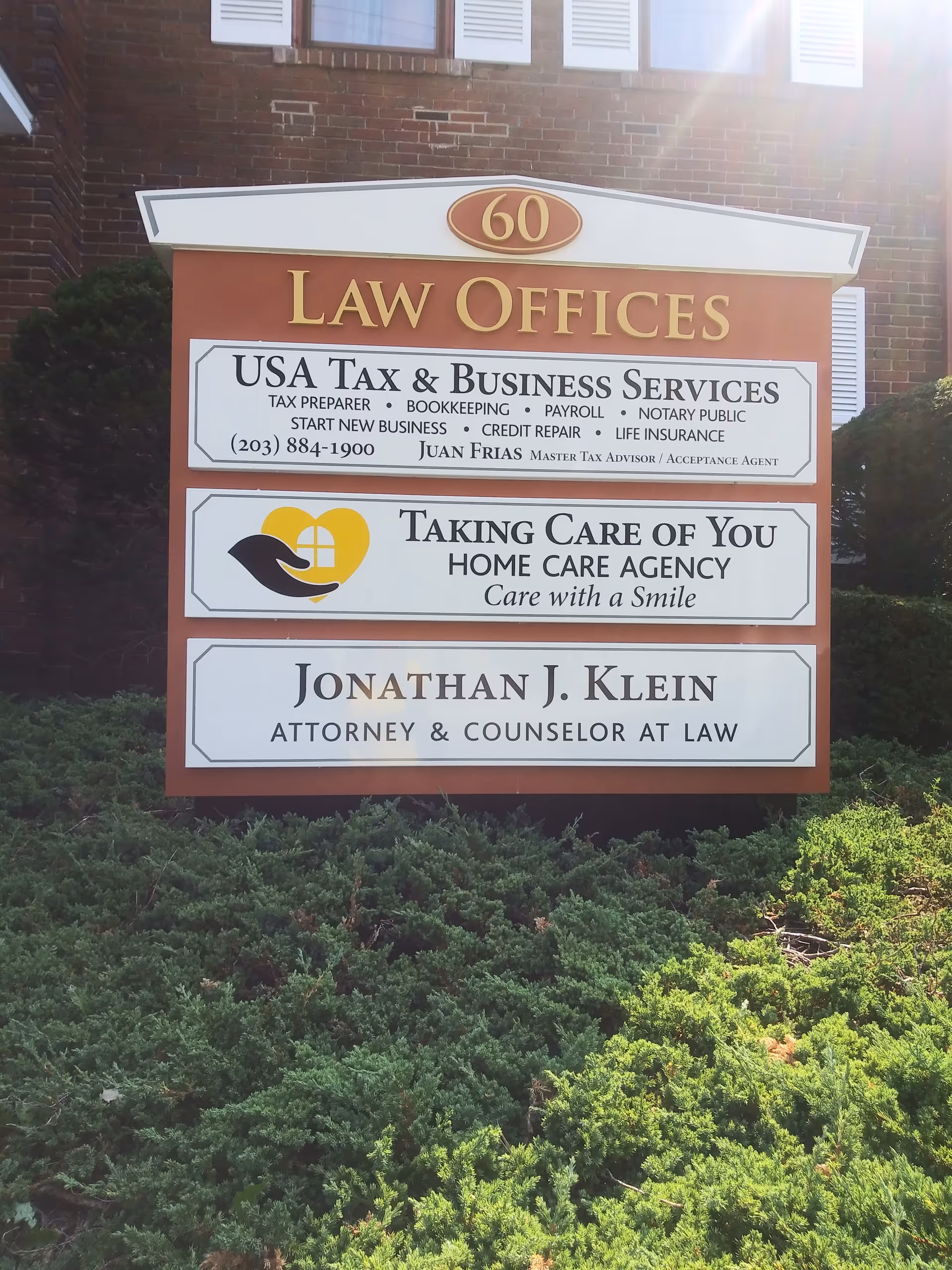 Exterior signboard on a brick building listing law offices and a home care agency.