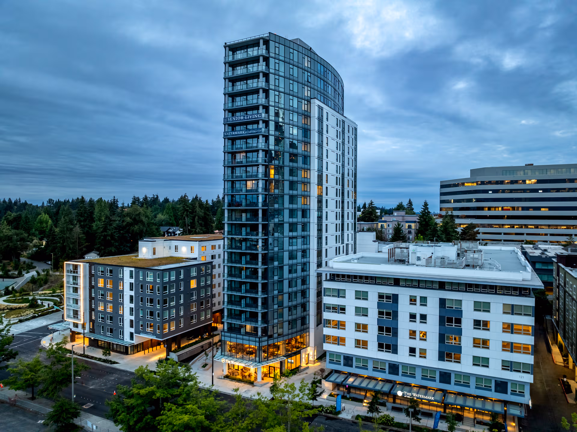 A modern multi-story senior living campus with glass towers and surrounding buildings.