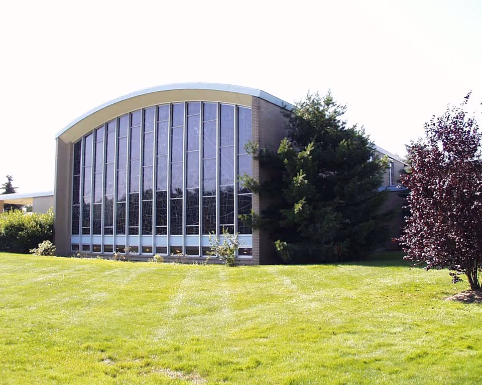 Windsor House exterior: curved roof, large glass windows, and a green lawn.